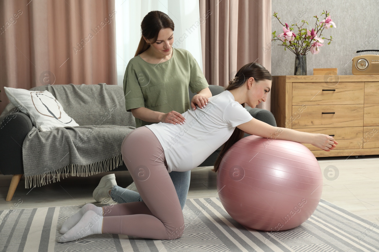 Photo of Doula massaging pregnant woman at home. Preparation for child birth