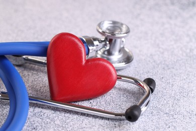 Photo of Stethoscope and red heart on grey stone table