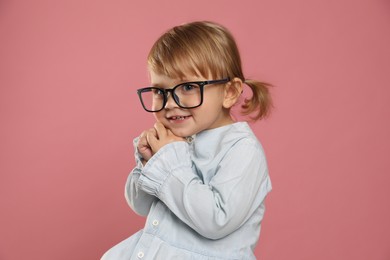Photo of Cute little girl in glasses on pink background