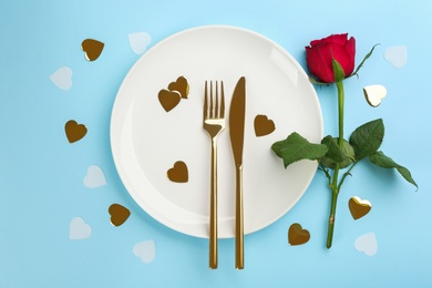 Beautiful table setting for Valentine's Day dinner on light blue background, flat lay