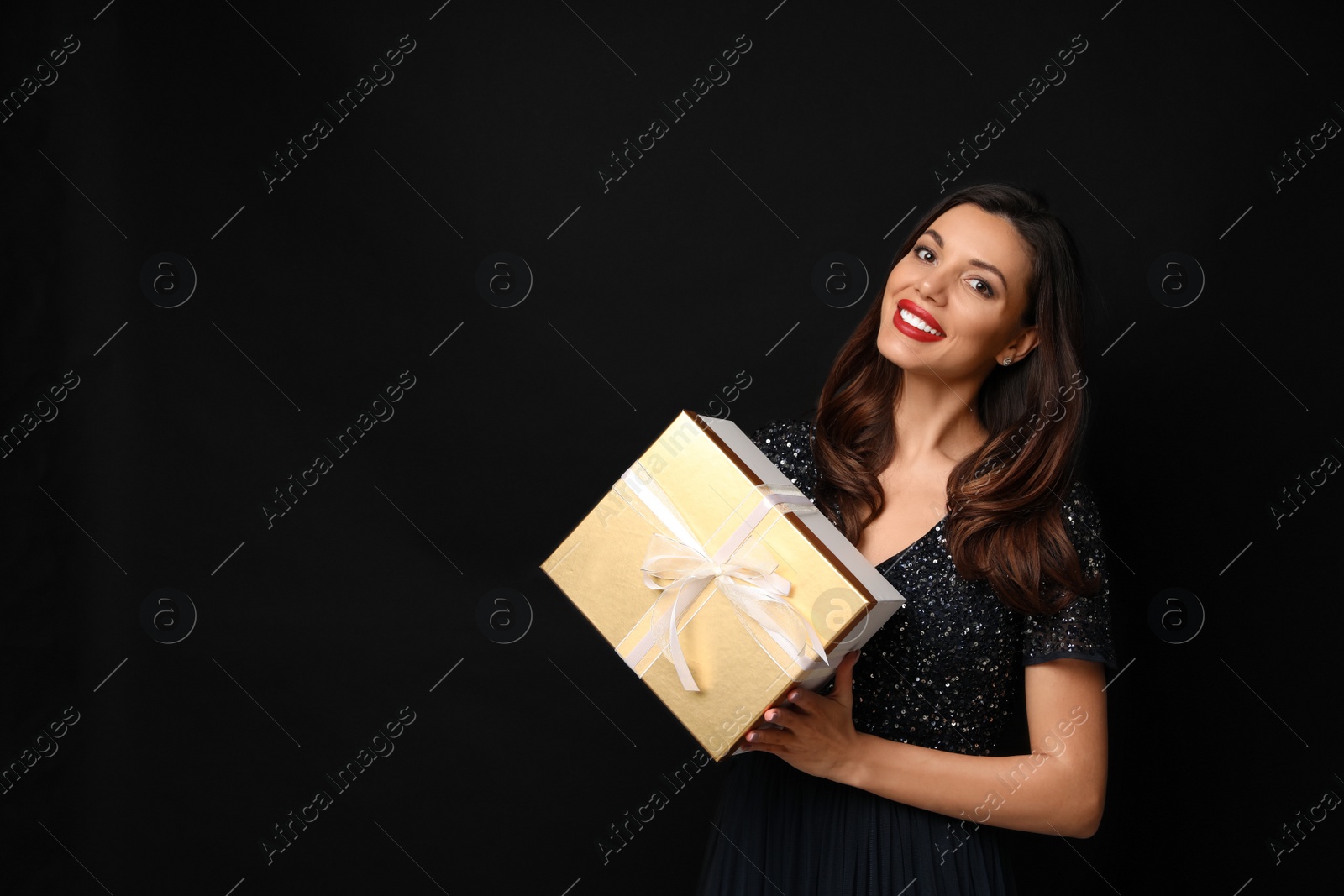 Photo of Beautiful woman with Christmas gift on black background