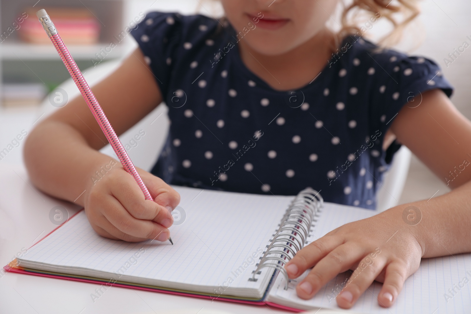 Photo of Little girl doing homework at table, closeup