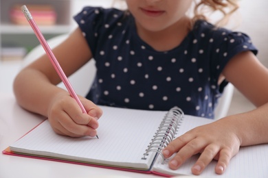 Little girl doing homework at table, closeup