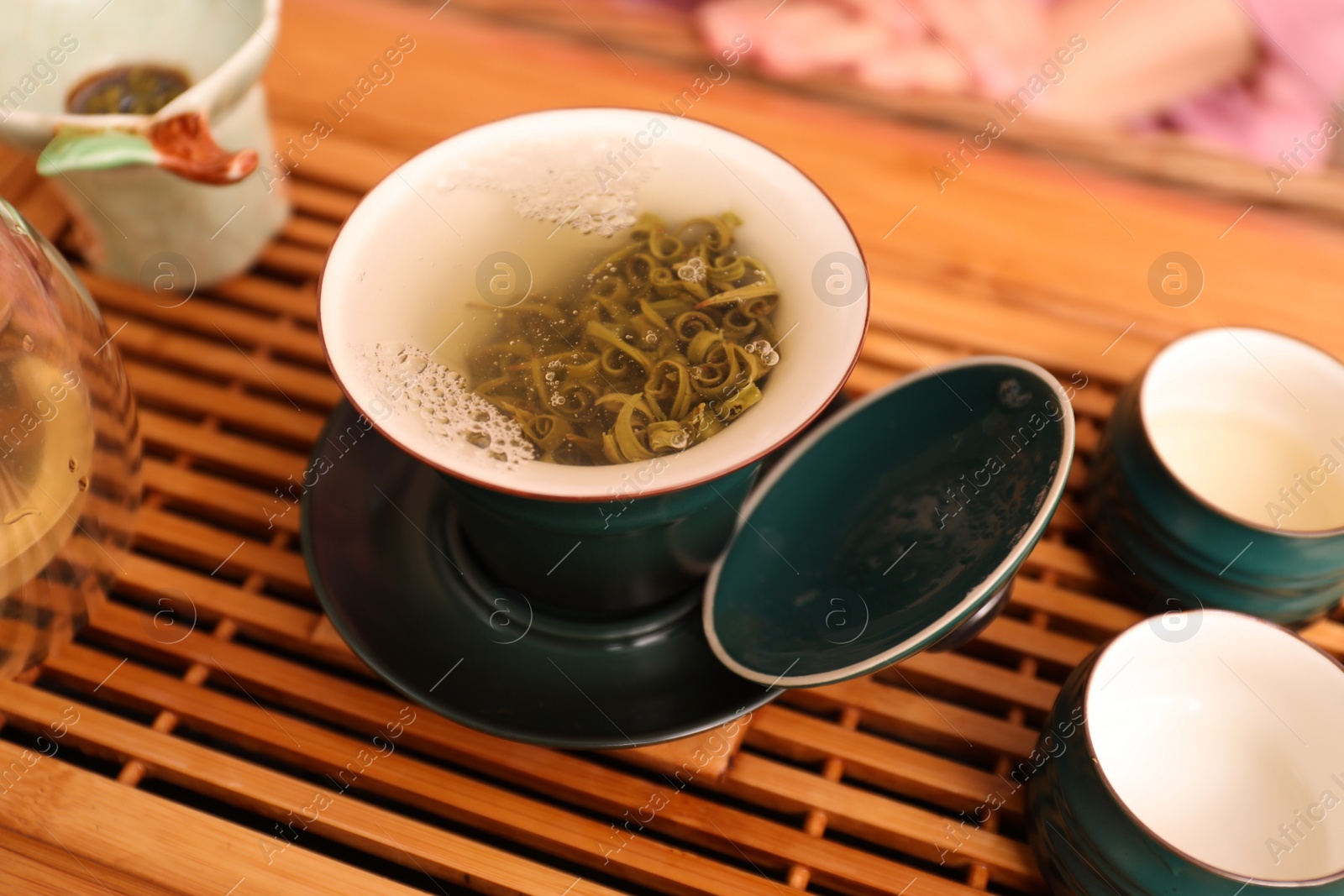 Photo of Cup with freshly brewed tea during traditional ceremony on wooden table