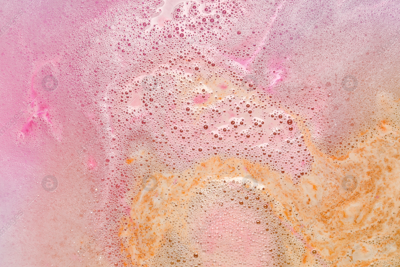 Photo of Colorful foam after dissolving bath bomb in water, closeup