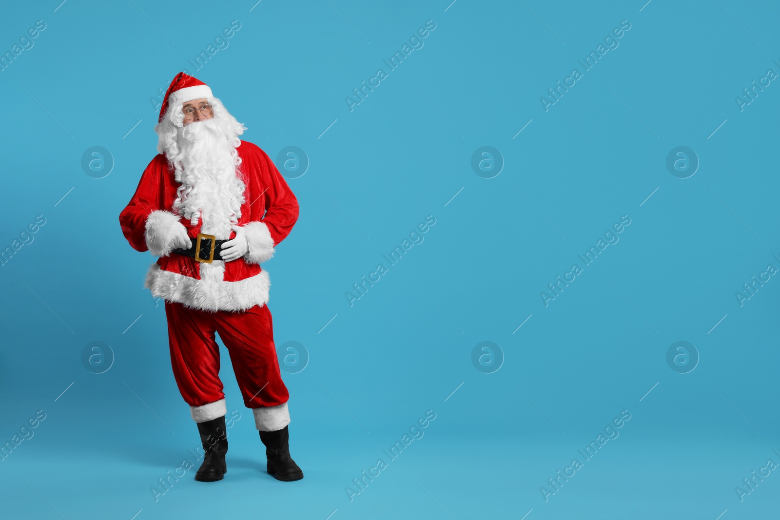 Photo of Merry Christmas. Santa Claus posing on light blue background, space for text