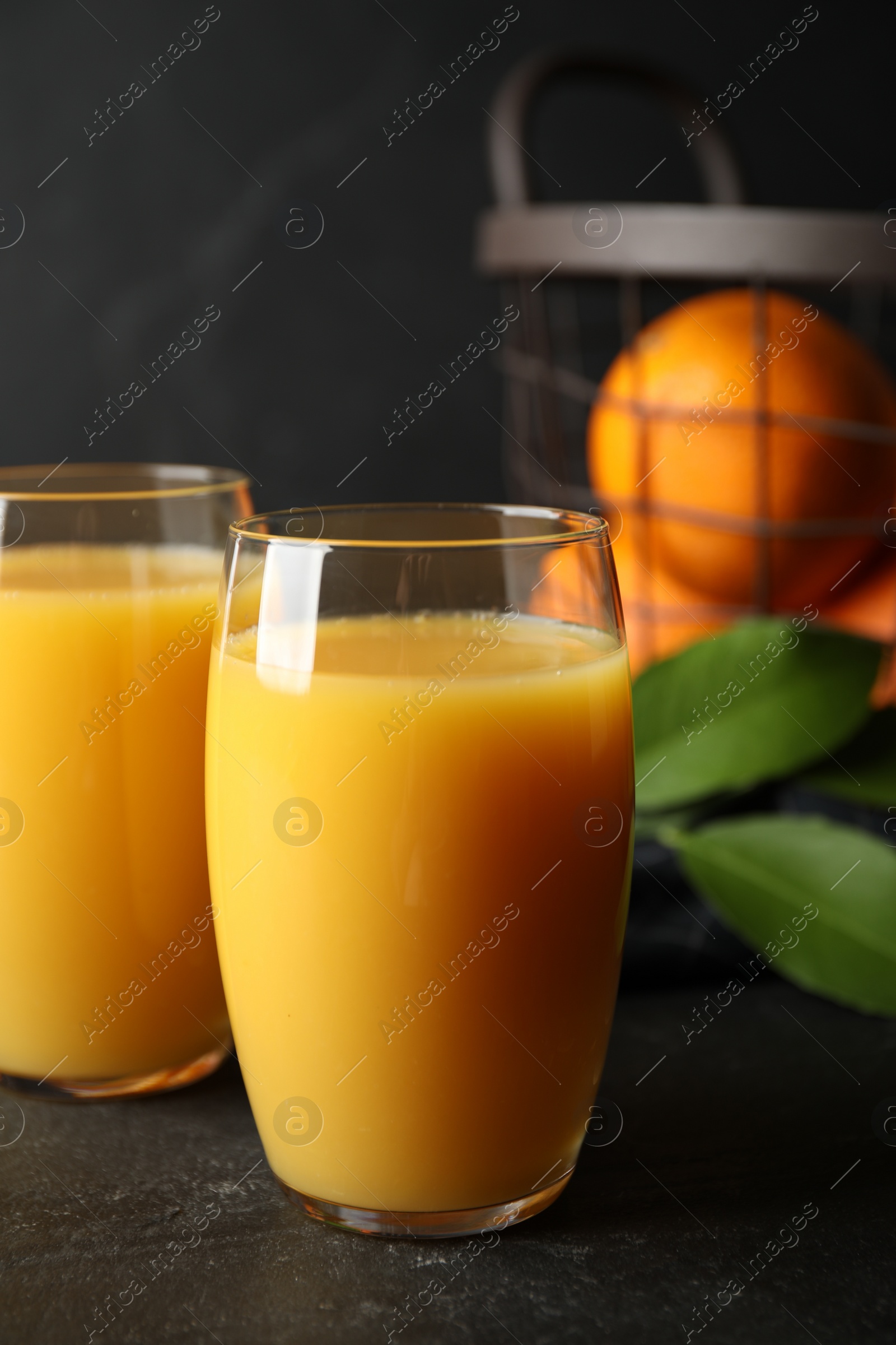 Photo of Glasses of orange juice on black table