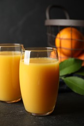 Photo of Glasses of orange juice on black table