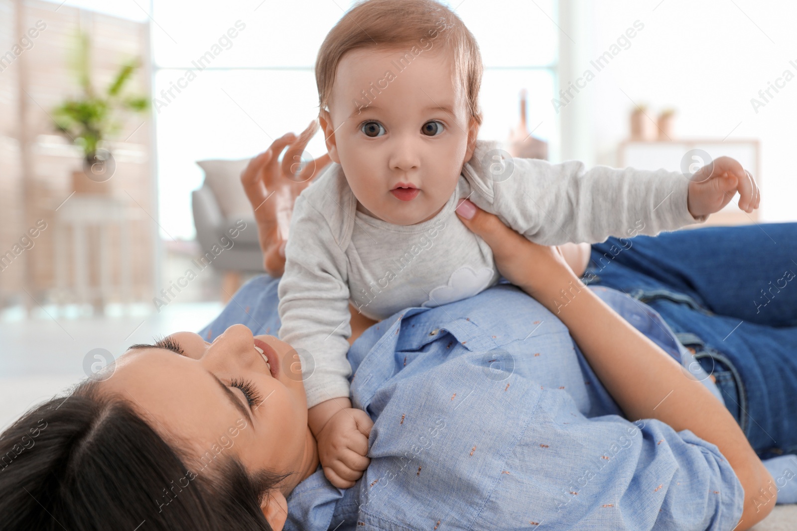 Photo of Happy young mother playing with baby on floor at home