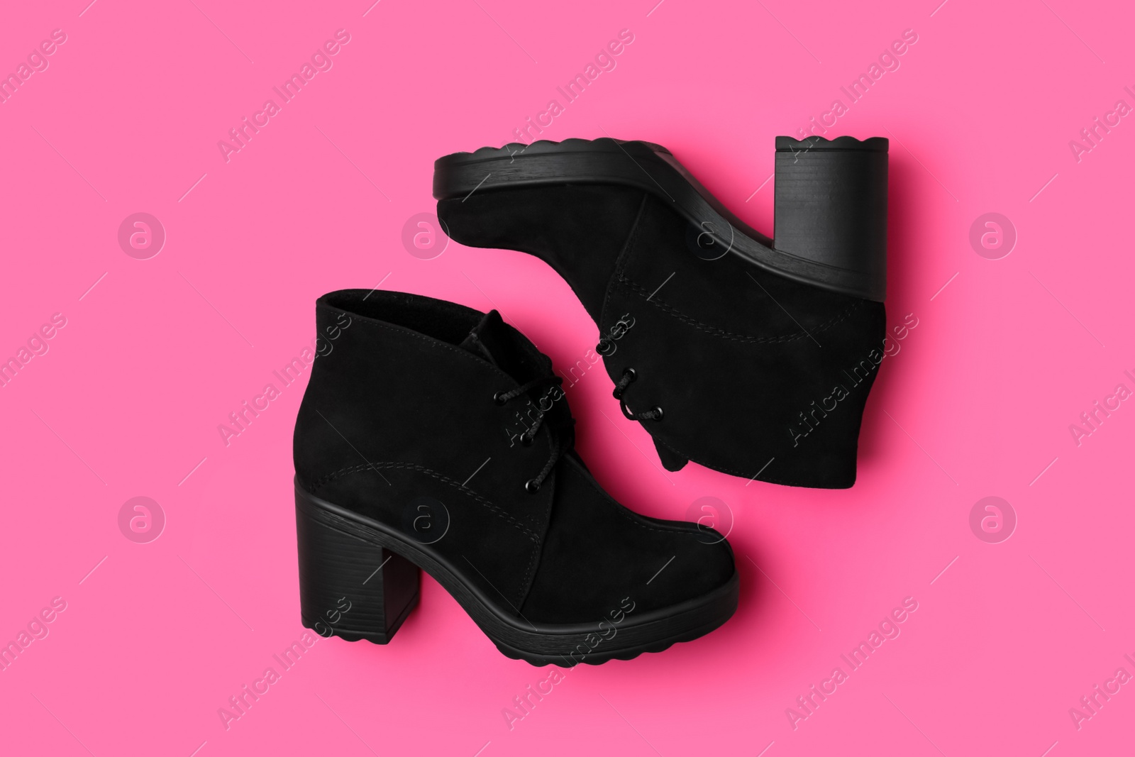 Photo of Stylish black female boots on pink background, flat lay