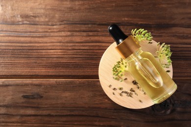 Bottle of essential oil, seeds and fresh dill on wooden table, top view. Space for text