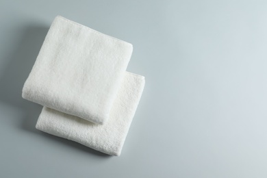 Soft folded towels on light background, top view with space for text