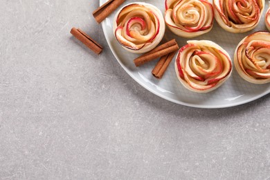 Freshly baked apple roses on grey table, top view. Space for text