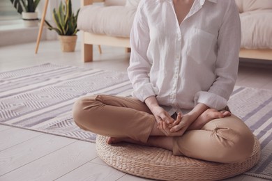 Photo of Woman meditating on wicker mat at home, closeup