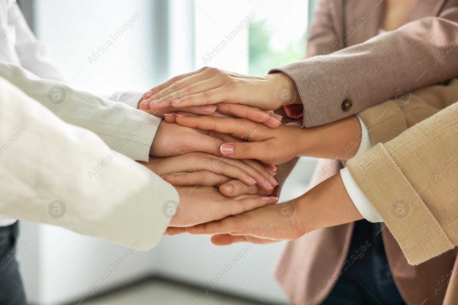 Photo of Group of people holding hands together indoors, closeup. Unity concept