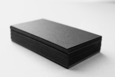 Photo of Blank black business cards on white table, closeup