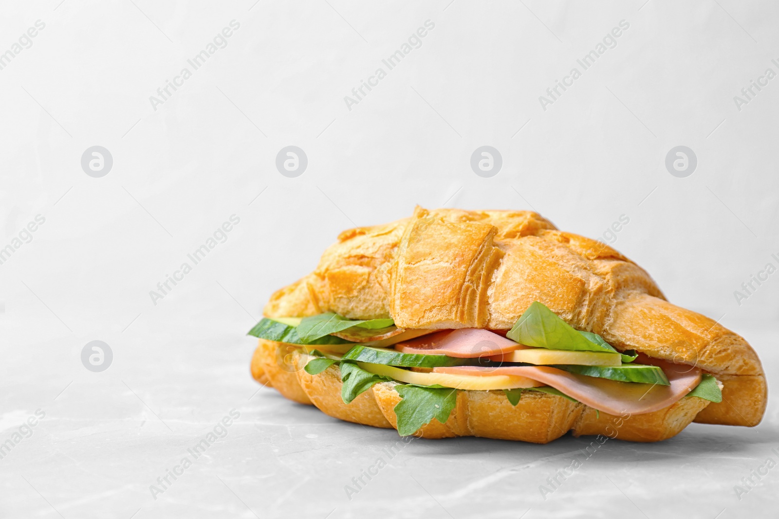 Photo of Tasty croissant sandwich with sausage on table