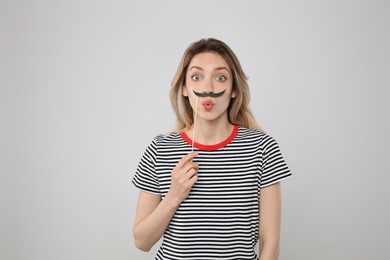Photo of Emotional woman with fake mustache on grey background