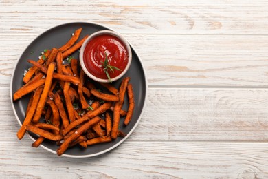 Delicious sweet potato fries served with sauce on white wooden table, top view. Space for text