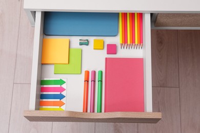 Photo of Office supplies in open desk drawer, above view