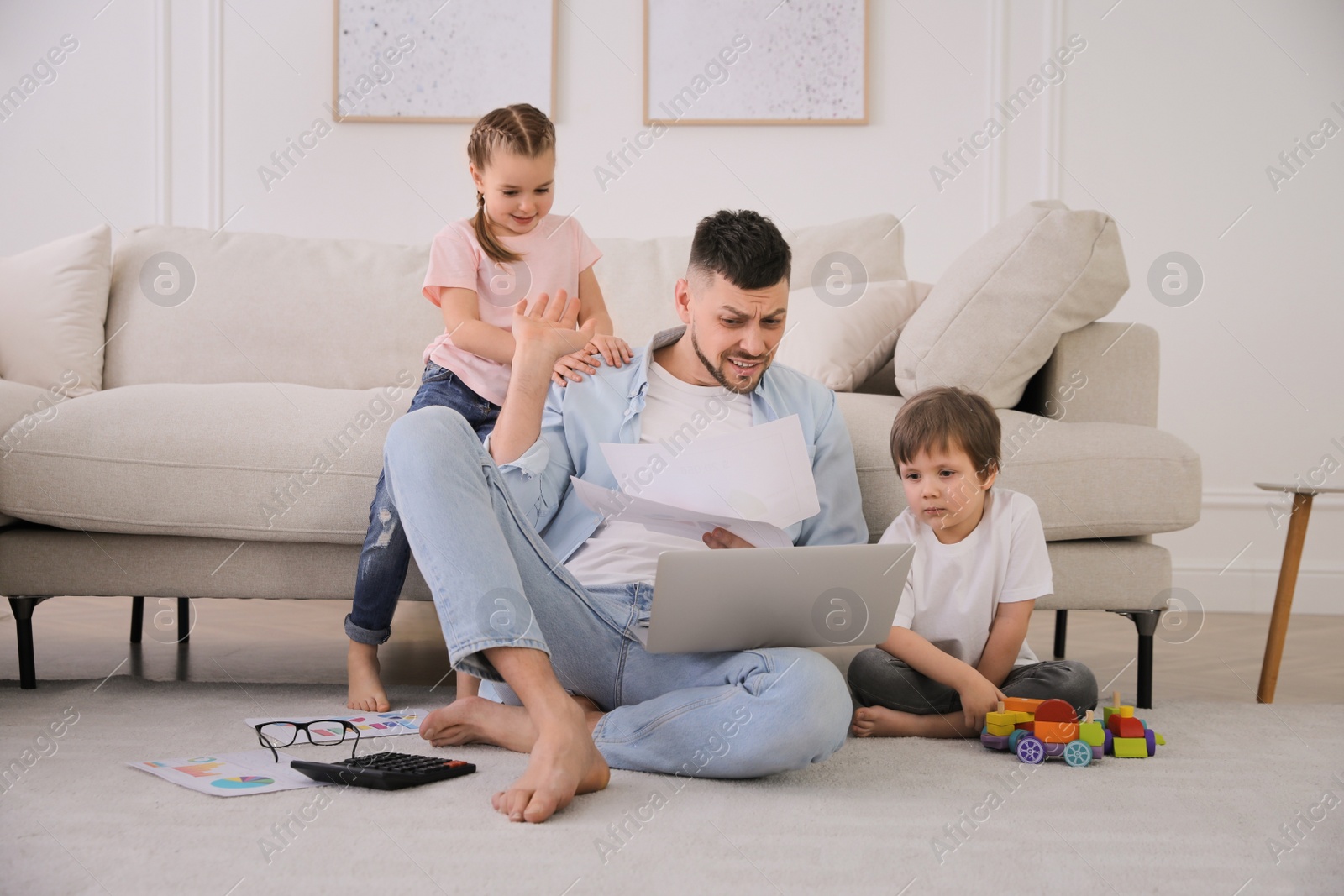 Photo of Overwhelmed man combining parenting and work at home