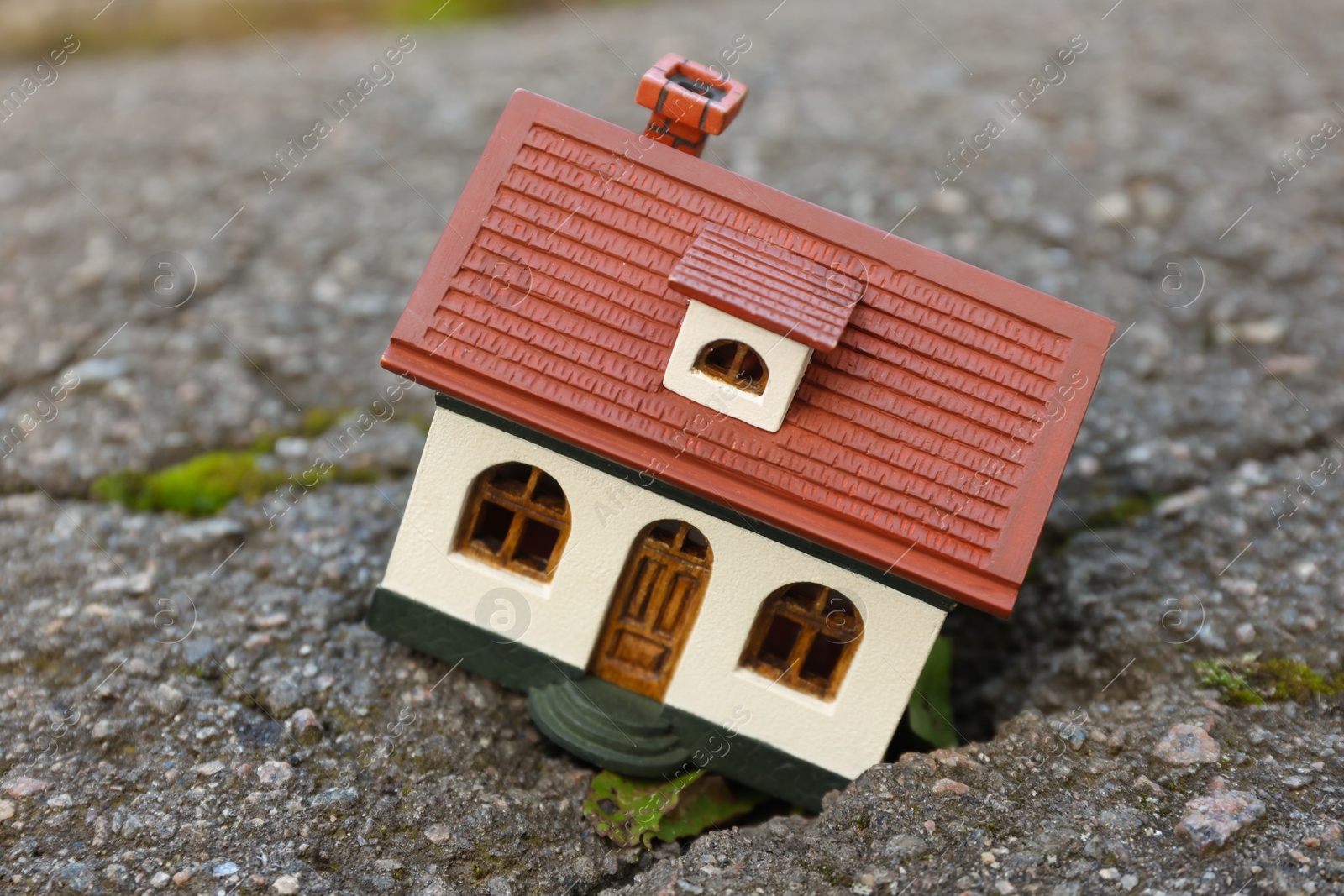 Photo of House model in cracked asphalt. Earthquake disaster