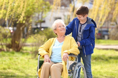 Photo of Senior woman in wheelchair with her grandson on sunny day outdoors