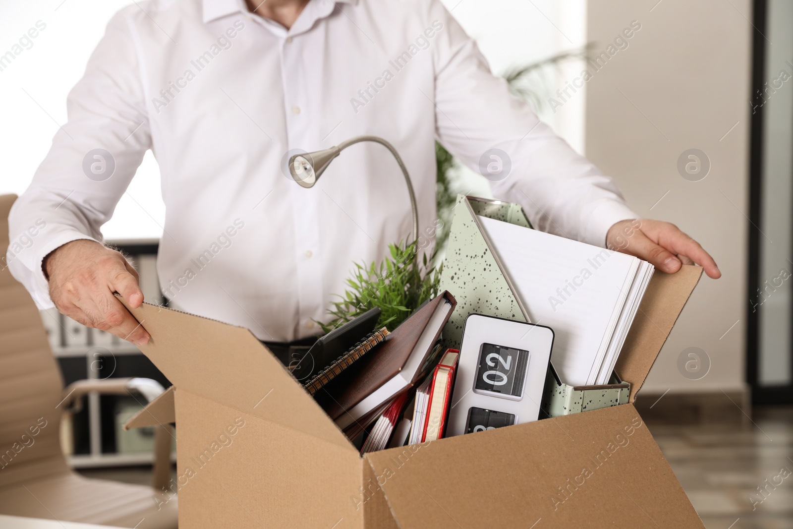 Photo of Young man with box of stuff in office, closeup