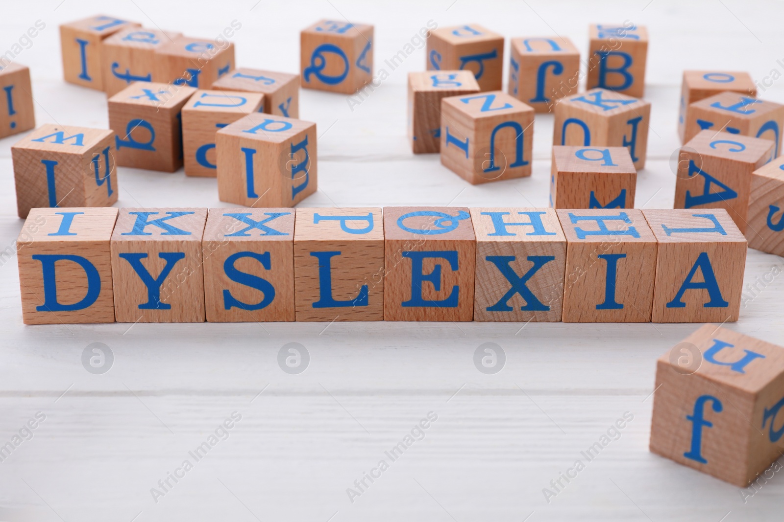Photo of Cubes with word Dyslexia on white wooden table