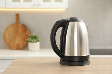 Photo of Modern electric kettle on table in kitchen. Space for text