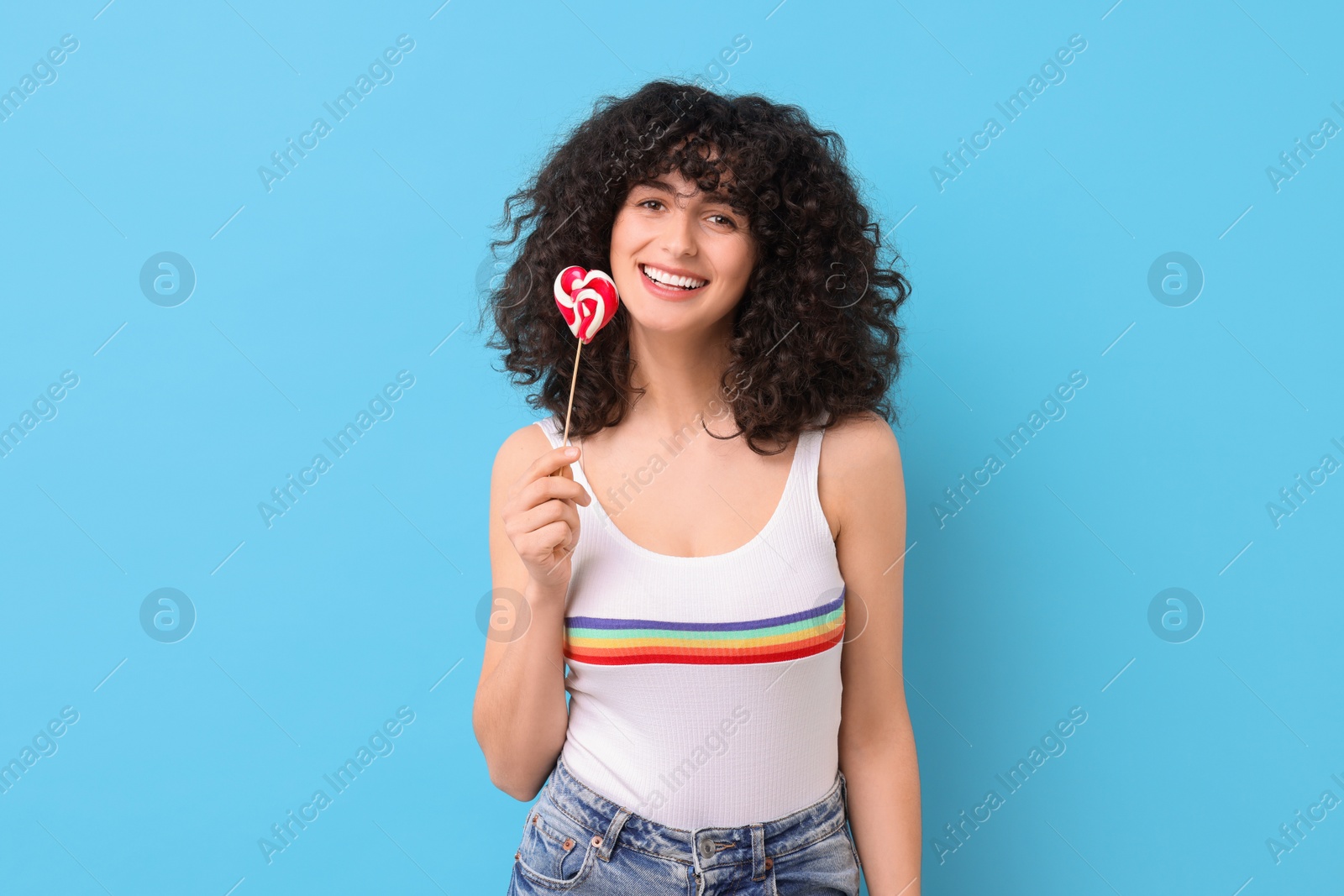 Photo of Beautiful woman with lollipop on light blue background