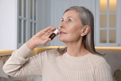 Photo of Medical drops. Woman using nasal spray indoors