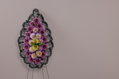 Photo of Funeral wreath of plastic flowers on grey background. Space for text