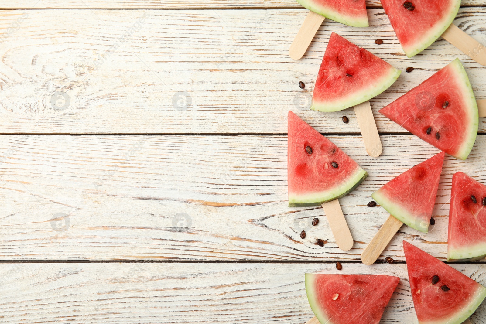 Photo of Slices of ripe watermelon on white wooden table, flat lay. Space for text