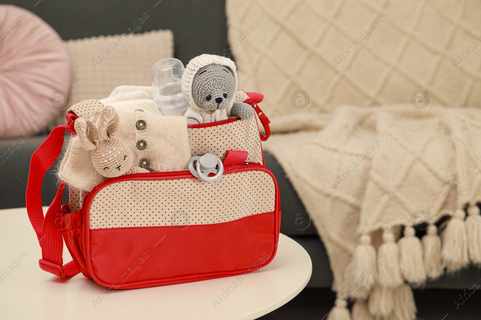 Photo of Mother's bag with baby's stuff on white table indoors. Space for text