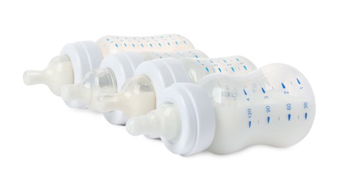 Feeding bottles with milk on white background
