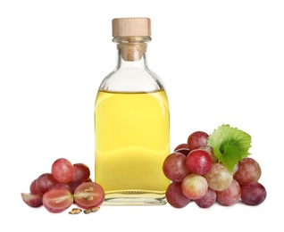 Organic red grapes, seeds and bottle of natural essential oil on white background