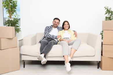 Photo of Happy couple resting on sofa in new apartment. Moving day