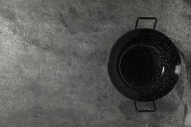 Photo of Empty iron wok on grey table, top view. Space for text