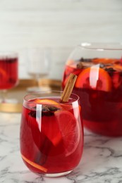 Photo of Glass and bowl of delicious aromatic punch drink on white marble table