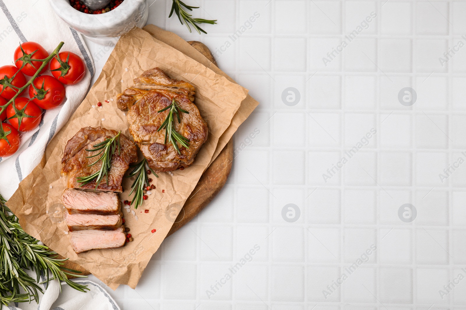 Photo of Delicious fried meat with rosemary served on white tiled table, flat lay. Space for text