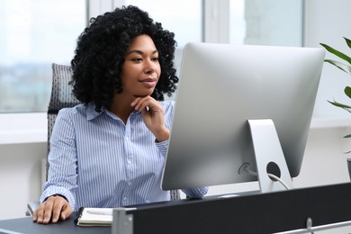 Photo of Young woman working on computer at table in office