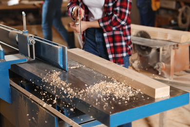 Photo of Female carpenter cleaning surface planer with air blow gun in workshop, closeup