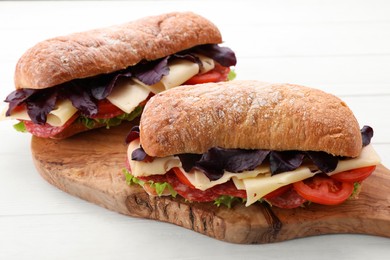 Delicious sandwiches with cheese, salami, tomato on white wooden table