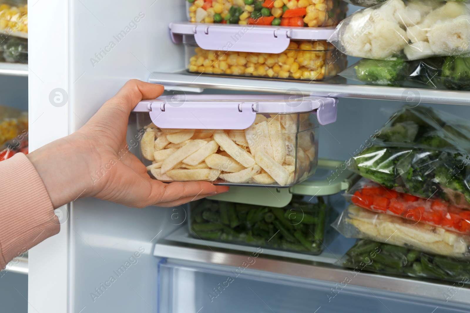 Photo of Woman taking container with frozen potato from refrigerator, closeup