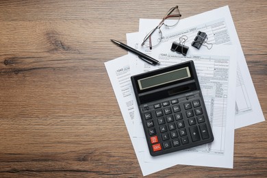 Photo of Calculator, documents, glasses and stationery on wooden table, flat lay with space for text. Tax accounting