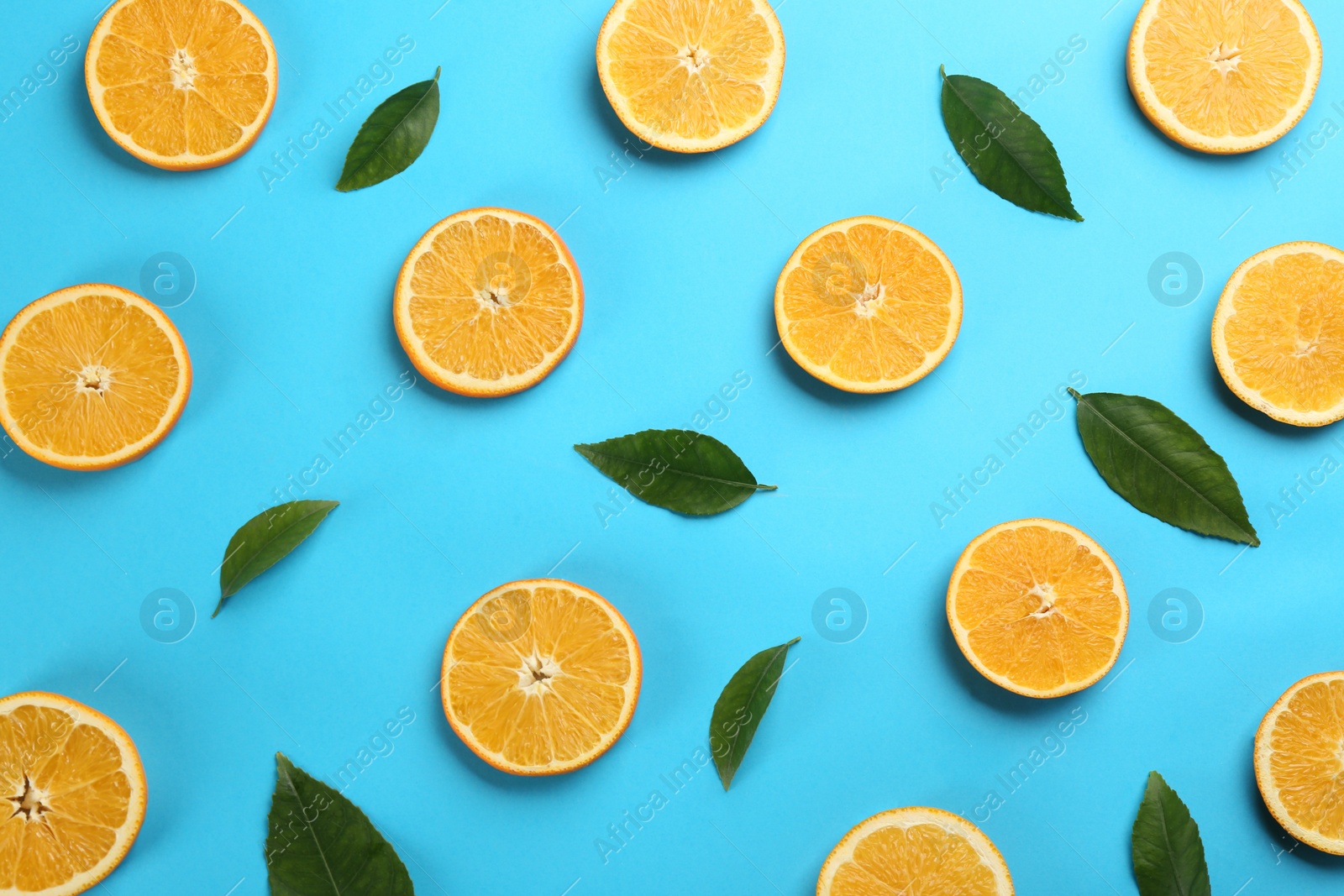 Photo of Slices of delicious oranges on light blue background, flat lay