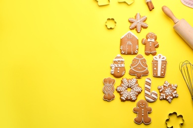 Photo of Kitchen utensils near Christmas tree shape made of delicious gingerbread cookies on yellow background, flat lay. Space for text