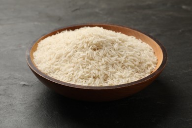 Photo of Raw basmati rice in bowl on black table