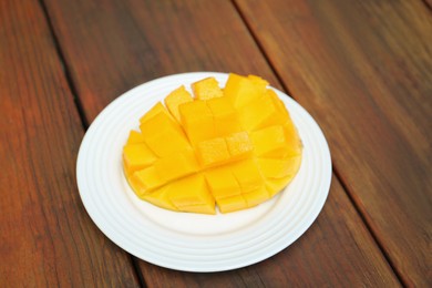 Photo of Delicious ripe cut mango on wooden table